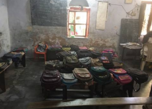 Classroom in India filled with benches and backpacks.
